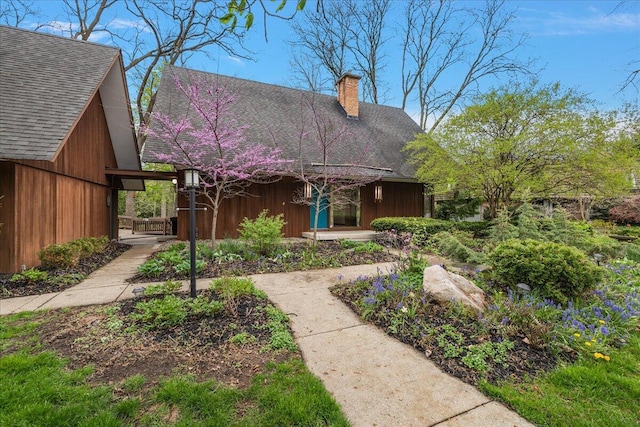 view of front of home with a shingled roof and a chimney