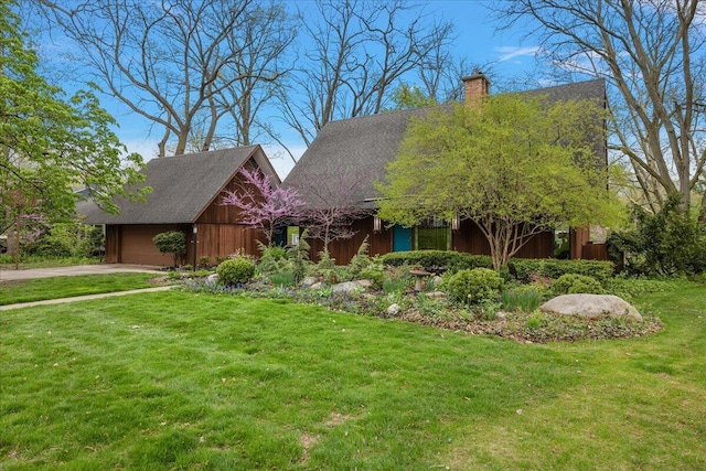 view of front of property with an attached garage, driveway, a chimney, and a front yard