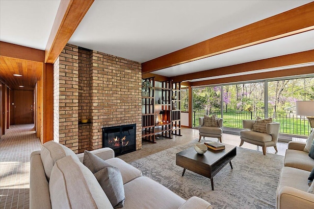 living area featuring carpet, beam ceiling, wood walls, and a brick fireplace