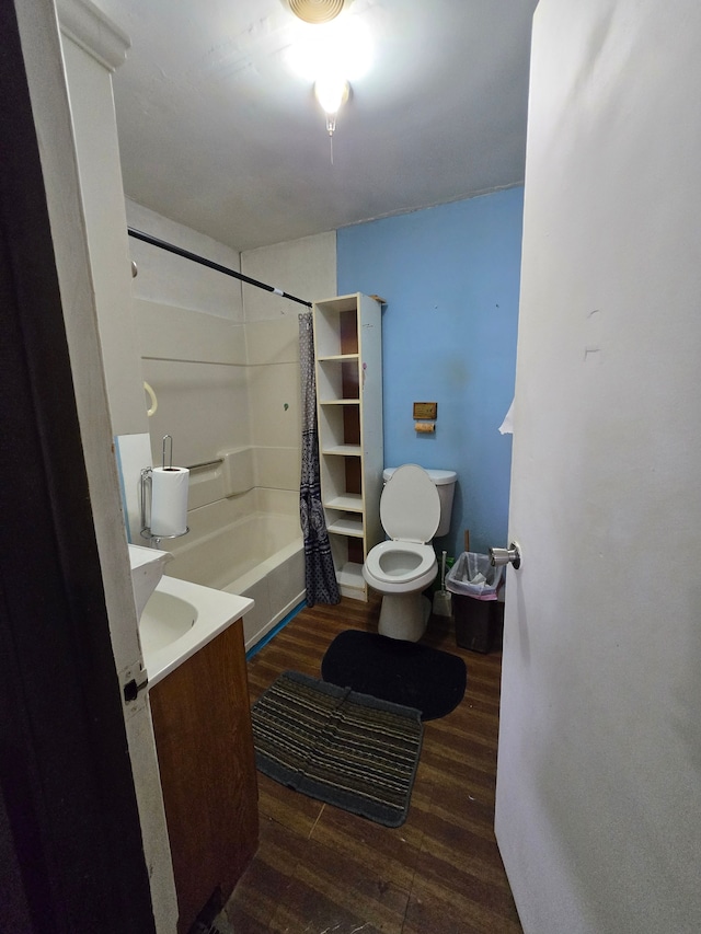 bathroom featuring toilet, wood finished floors, vanity, and shower / washtub combination