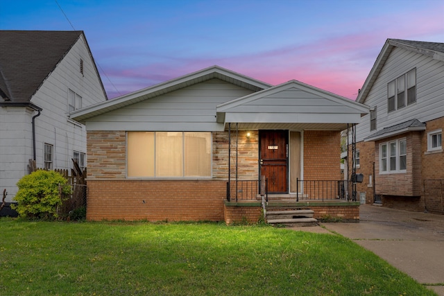 bungalow featuring brick siding, a front yard, and a porch