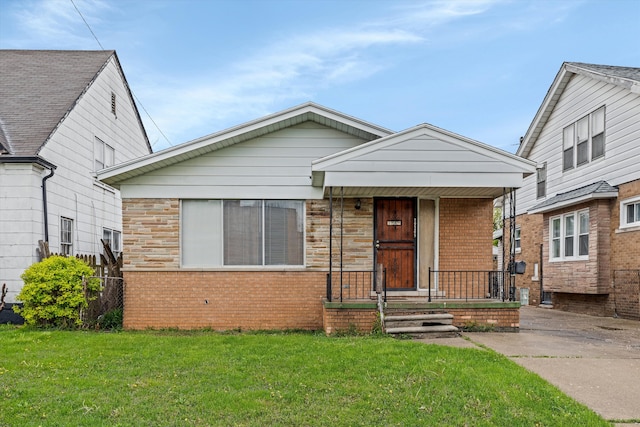bungalow featuring a front yard, brick siding, and covered porch