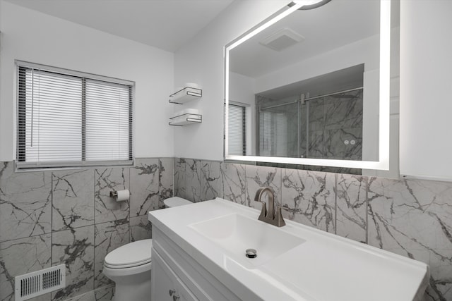 full bath with toilet, a stall shower, tile walls, visible vents, and vanity