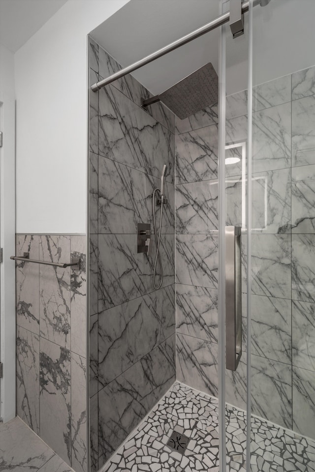 full bath with a stall shower, tile walls, a wainscoted wall, and marble finish floor