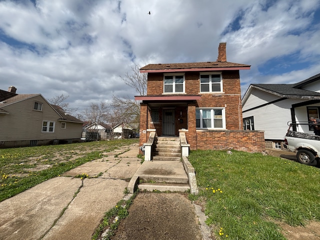 view of front facade with a chimney, a front yard, and brick siding