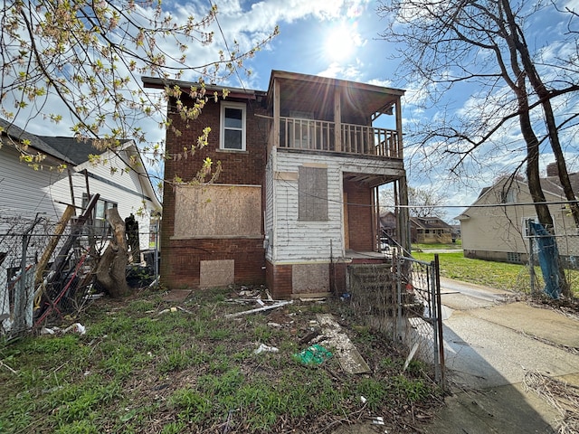 view of front of house featuring fence, brick siding, and a balcony