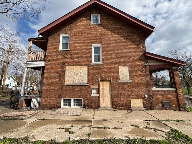 rear view of property featuring a patio, brick siding, and a balcony