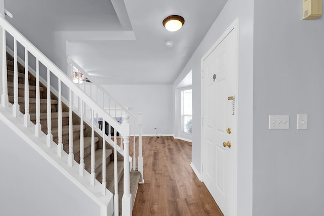 entryway featuring wood finished floors, baseboards, and stairs