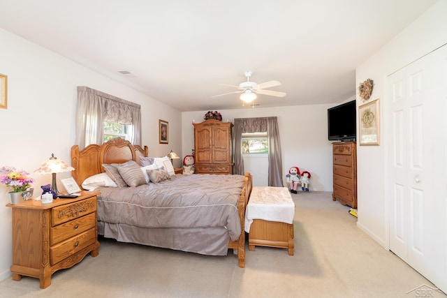 bedroom with light carpet, multiple windows, and a ceiling fan