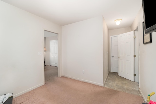 unfurnished bedroom with light colored carpet and baseboards