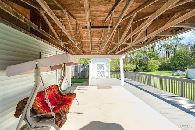 view of patio featuring fence, a shed, and an outbuilding