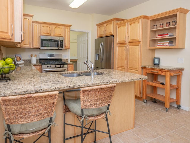 kitchen with light brown cabinetry, open shelves, appliances with stainless steel finishes, and a sink