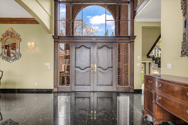 entrance foyer featuring crown molding, a towering ceiling, baseboards, and granite finish floor