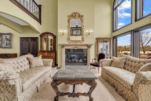 carpeted living area with a fireplace, a high ceiling, and arched walkways