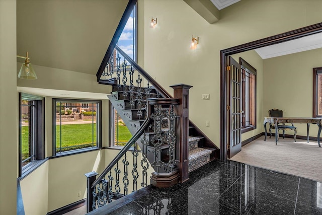 staircase featuring crown molding, a wealth of natural light, baseboards, and granite finish floor