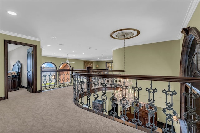hall with crown molding, carpet floors, baseboards, and an upstairs landing