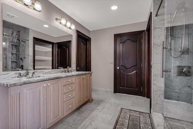 bathroom featuring a sink, marble finish floor, a stall shower, double vanity, and baseboards