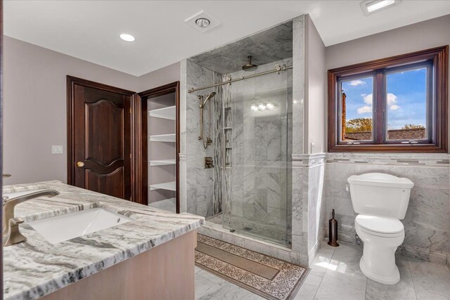 full bath with toilet, a sink, tile walls, a shower stall, and marble finish floor