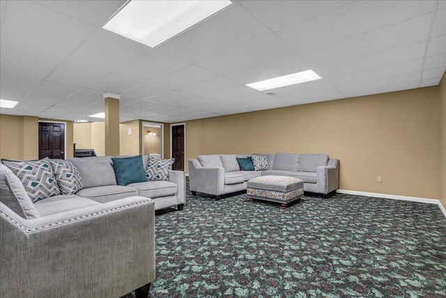 carpeted living area with baseboards and a drop ceiling