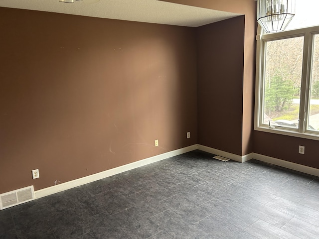 unfurnished room with baseboards and visible vents