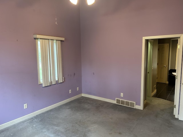 unfurnished room featuring dark colored carpet, baseboards, and visible vents