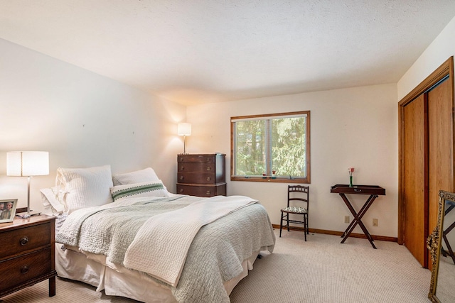 bedroom with a closet, light carpet, and baseboards