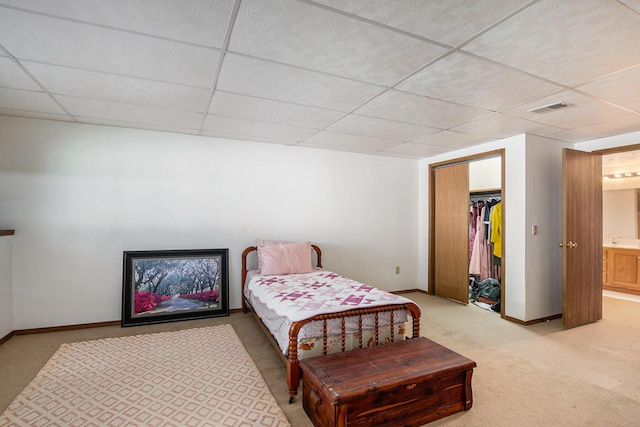 bedroom featuring a paneled ceiling, light colored carpet, baseboards, and visible vents
