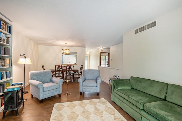 living area with baseboards, an inviting chandelier, visible vents, and wood finished floors