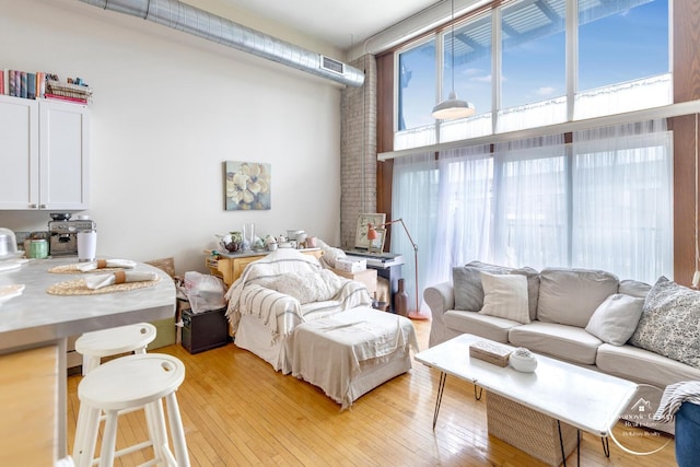 bedroom with light wood finished floors, visible vents, and a towering ceiling