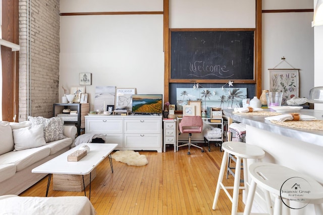 living area featuring light wood-style flooring and brick wall