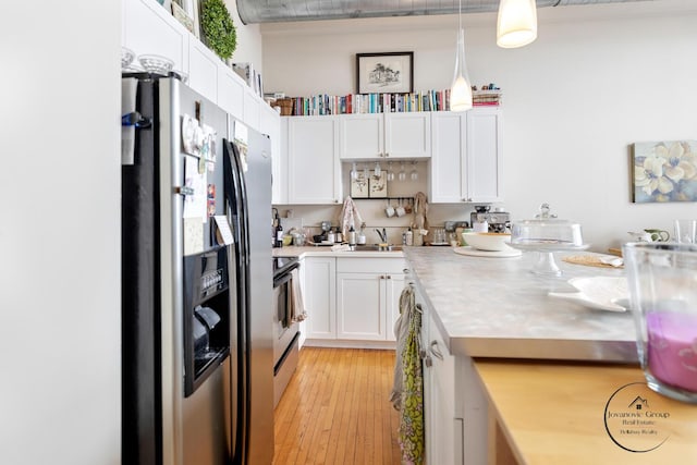 kitchen featuring a sink, light wood-type flooring, white cabinetry, light countertops, and appliances with stainless steel finishes