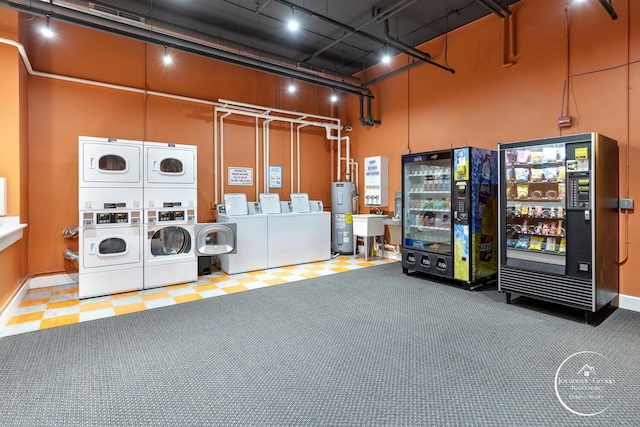 common laundry area with stacked washer / dryer, water heater, a high ceiling, and independent washer and dryer