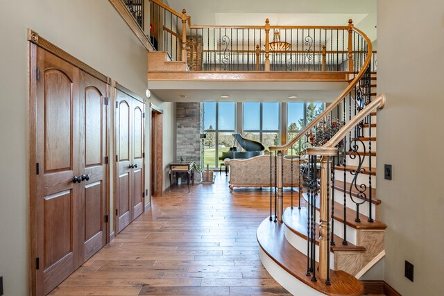 entryway featuring hardwood / wood-style flooring, a towering ceiling, stairway, and baseboards
