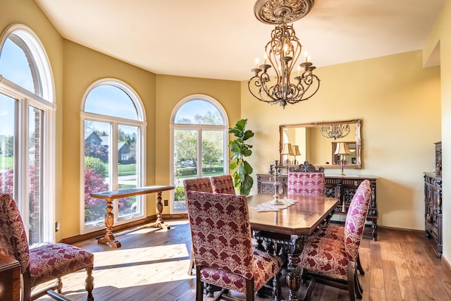 dining room featuring hardwood / wood-style floors, a chandelier, and baseboards