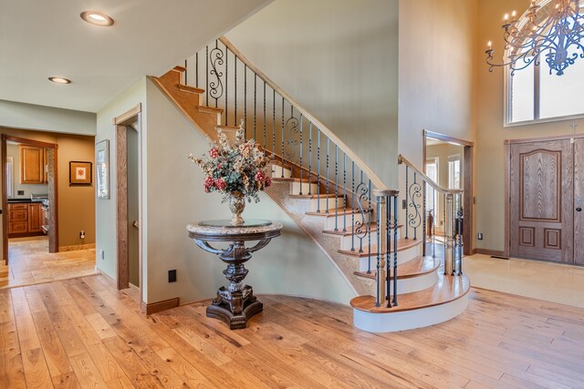 foyer featuring hardwood / wood-style floors, stairway, recessed lighting, a towering ceiling, and baseboards