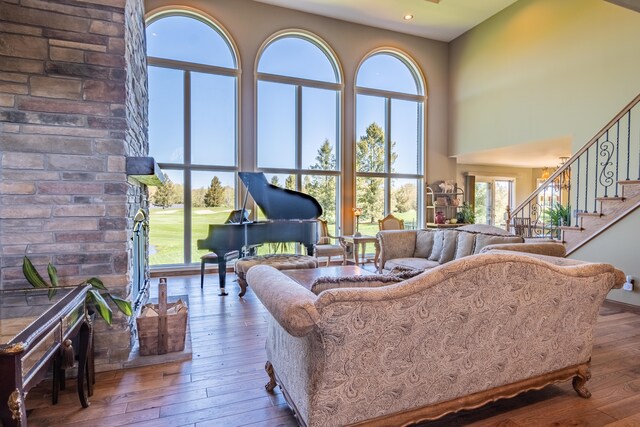 living area with a towering ceiling, hardwood / wood-style floors, recessed lighting, and stairs