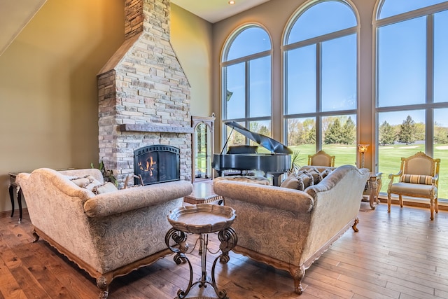living area featuring a high ceiling, a fireplace, wood-type flooring, and recessed lighting