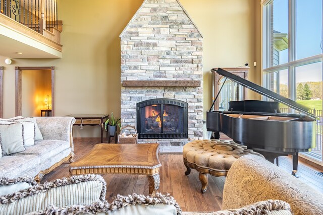 living room featuring hardwood / wood-style floors, a fireplace, healthy amount of natural light, a towering ceiling, and baseboards