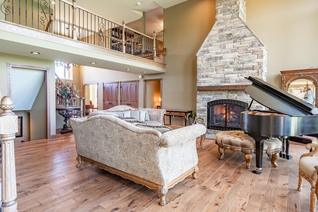 living area featuring a stone fireplace, hardwood / wood-style floors, and a high ceiling