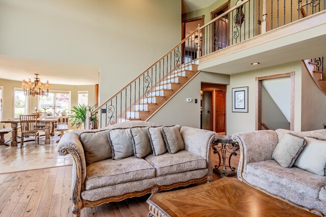 living area with stairway, a high ceiling, a chandelier, and wood-type flooring