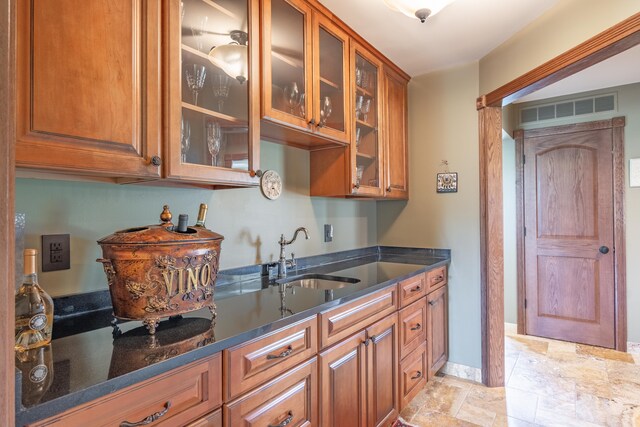 bar area with a sink, stone tile flooring, and baseboards