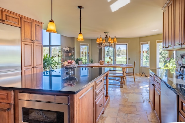 kitchen featuring appliances with stainless steel finishes, stone tile floors, a chandelier, brown cabinets, and decorative light fixtures