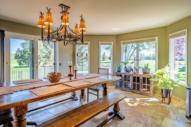 dining space featuring stone tile floors and a chandelier