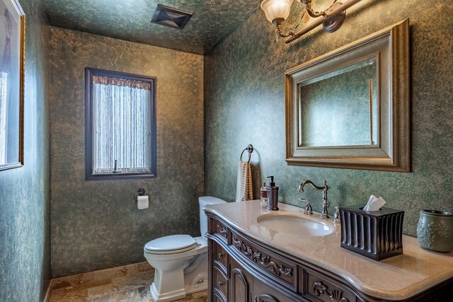 bathroom with stone finish floors, toilet, and vanity