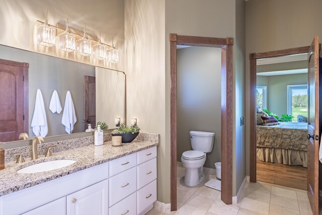 bathroom with ensuite bathroom, toilet, vanity, baseboards, and tile patterned flooring