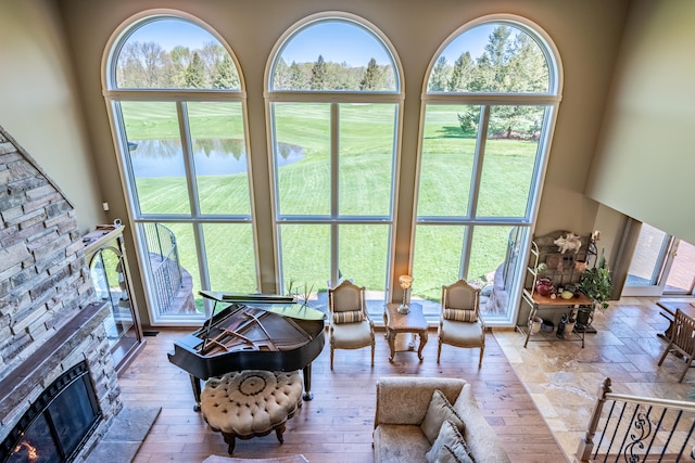 living area featuring a water view, a stone fireplace, and healthy amount of natural light