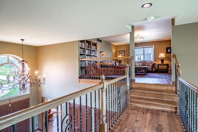 hall featuring a chandelier, hardwood / wood-style flooring, and an upstairs landing