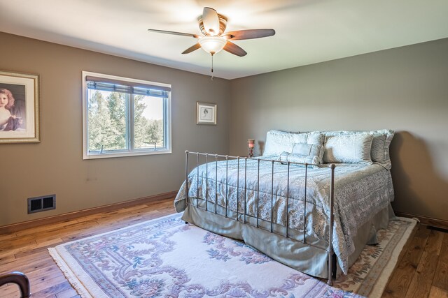 bedroom with hardwood / wood-style floors, baseboards, and a ceiling fan