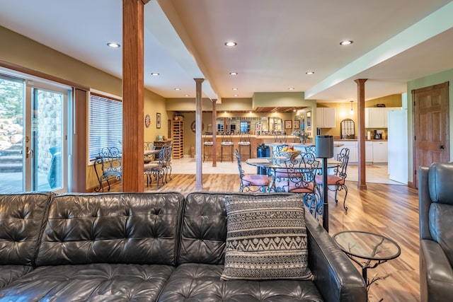 living area with light wood-style flooring, ornate columns, and recessed lighting