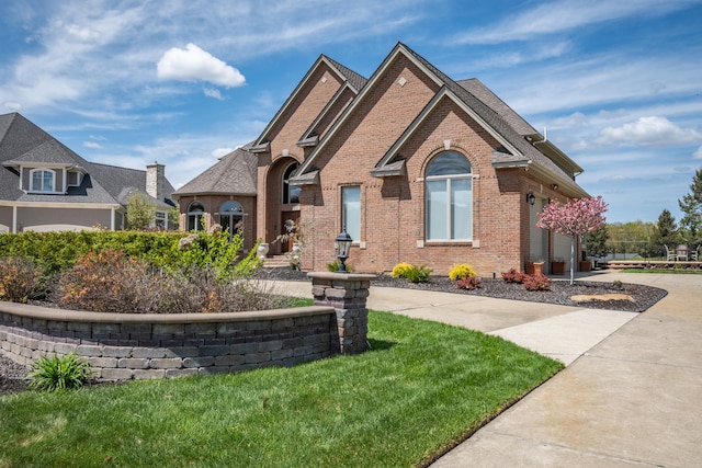 view of front facade with brick siding, a garage, concrete driveway, and a front yard
